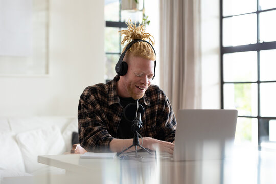 Happy albino african american man with dreadlocks working from home and making podcast - Powered by Adobe
