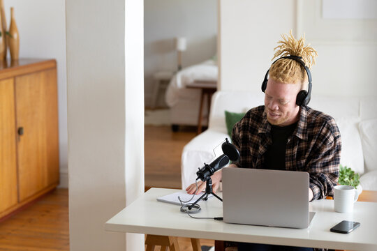 Happy albino african american man with dreadlocks working from home and making podcast - Powered by Adobe