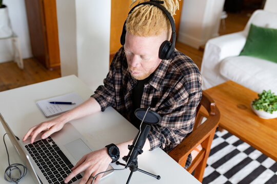 Happy albino african american man with dreadlocks working from home and making podcast - Powered by Adobe