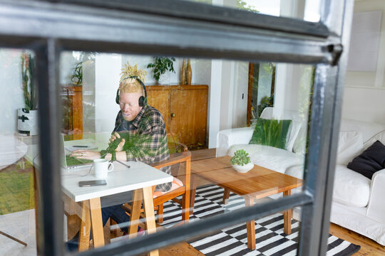 Happy albino african american man with dreadlocks working from home and making podcast - Powered by Adobe
