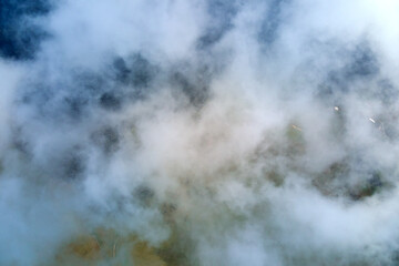 Aerial view from airplane window at high altitude of earth covered with white puffy cumulus clouds.