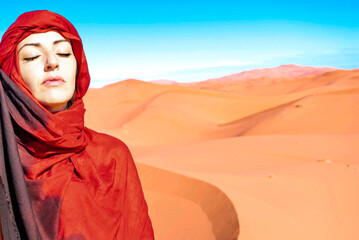 Portrait of a Caucasian woman meditating with a red headscarf in the desert sun.