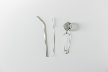 Frame with straw, cleaning brush and tea strainer on white background. Flat lay, top view, copy space. Minimalist concept.