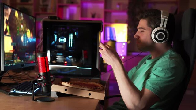 Side view of a professional player watching a video game match and eating a pizza
