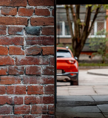 Red brick wall on one half and red car in the blur on the other half (1044)