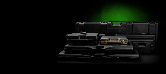 A variety of plastic cases for weapons. Strong containers for storing and transporting weapons against a dark back with a green spot of light.