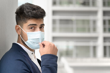 Portrait of a Handsome man in medical mask looking to camera at city. Handsome young man standing outdoors in medical mask. Coronavirus concept. High quality photo