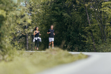 Fototapeta premium Young fit couple atheltes running on running road in a forest.