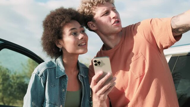 Concentrated man showing the way to smiling african girl in nature