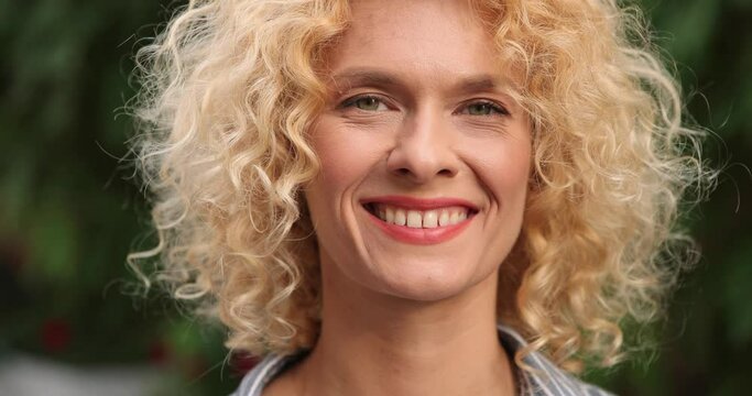 Close up of caucasian joyful woman smiling outdoor. Happy girl standing on street in good mood. Female in city with smile on face. Portrait concept