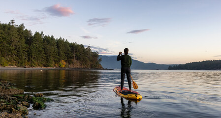 Adventurous Caucasian Adult Woman on a Stand Up Paddle Board is paddling on the West Coast of...