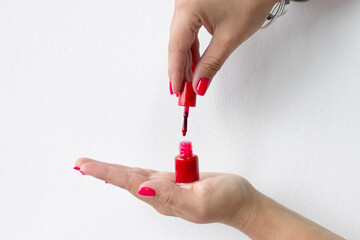 Women's hands with beautiful nails hold a bottle of nail polish on a white background, the concept of professional nail care. With a copy of the space. Close-up
