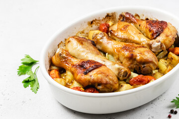 Honey mustard chicken legs with root vegetables in baking dish.Copy space.