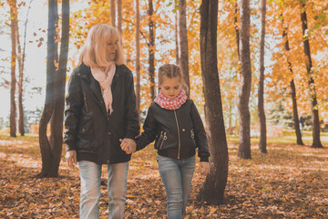 Grandmother with granddaughter in autumn park. Generation and family concept.