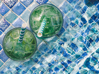 Beautiful glass with a refresh cocktail on the background of the pool. View from above, close-up. Vacation and travel concept