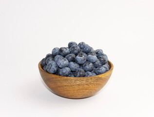 ripe blueberries in a wooden bowl on a white background