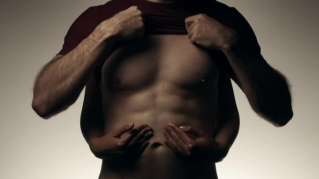 Female hands slowly touching torso with abs of male