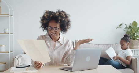 Annoyed african woman, single mom, sitting at table with laptop, dealing with financial problems, feeling pressure because of mortgage debt, feeling anxious over money and utility bills