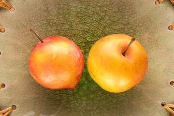 Two juicy sweet yellow-red plums on a ceramic plate, close-up, top view.