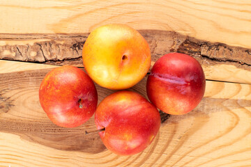 Several juicy sweet yellow-red plums on a wooden table, close-up, top view.