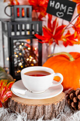  A cup of tea with lemon, autumn leaves and pumpkin. The concept of a cozy autumn at home vertical photo