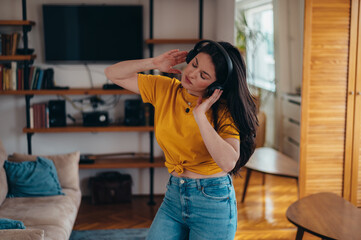 Woman dancing while listening a music on a headphones at home