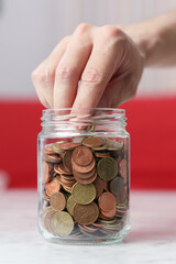 Hand picking up a coin from a glass jar