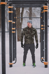 Training outside in winter in a snowfall. a man is resting between exercises on a sports field in a snowstorm