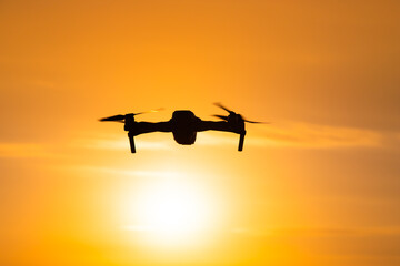 The drone is in flight at sunset . Video shooting from above. An article about the choice of a quadrocopter. Pros and cons of the drone.