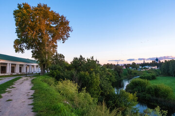 Fototapeta na wymiar Evening landscape in the city of Suzdal with the Kamenka River and a tall tree.