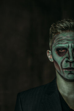 A man in the image of Frankenstein, green makeup, dark jacket, Halloween. The image of a man on Halloween