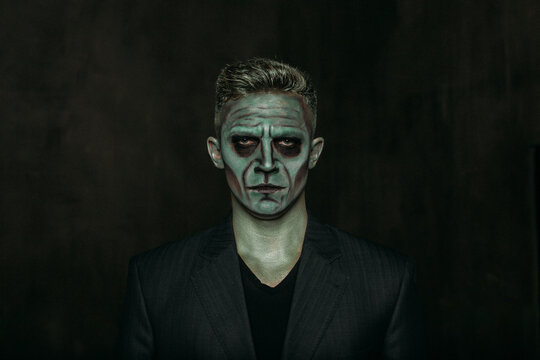 A man in the image of Frankenstein, green makeup, dark jacket, Halloween. The image of a man on Halloween