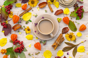autumn composition cup of coffee on a table with flowers and leaves, top view, background picture


