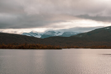 Fototapeta na wymiar Lake and snowy mountains on a cloudy day in autumn