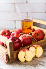 Wooden tray full of fresh red apples and glass of juice with straw. Concept of healthy life