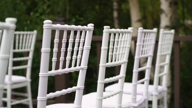 White plastic Chiavari chairs in rows. Outdoor wedding ceremony.