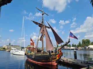 Fototapeta na wymiar The reconstructed wooden sailing ship Libava docked at the pier in the Latvian port of Riga on a hot summer day in 2021