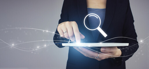 White tablet in businesswoman hand with digital hologram sign on grey background.
