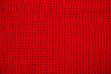 Knitted surface of woolen things as a background. Close-up of soft fabric red color knitted patterns texture. Warm winter clothing. Background textile surface with copy space for text.