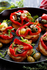 Bruschetta, toasted bread  with mozzarella cheese and roasted red pepper with capers, olives and herbs, close up view