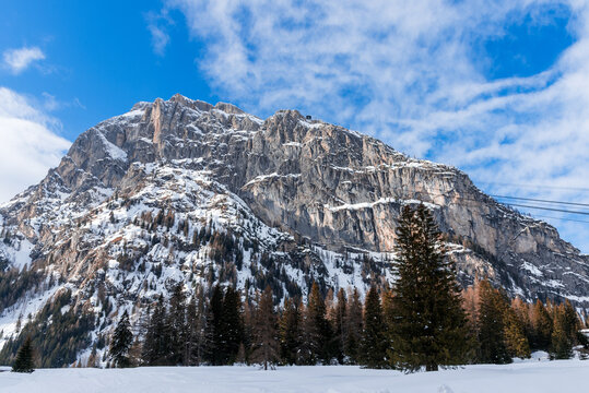 Snow covered rocky peak in the European Alps on a clear winter day. A cable car station is visible on the top of the mountain.