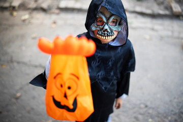 Little boy in halloween costume and mask holding a special candy bag in his hand. Trick or treat