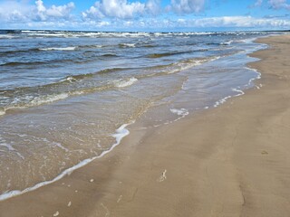 Sandy seashore and blue sky with slight white clouds on a hot summer day