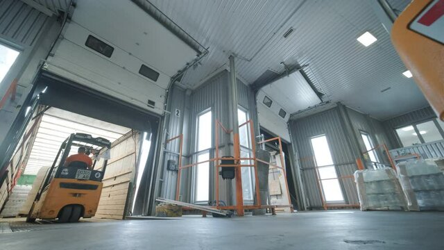 Forklift driver transports packaged water bottles in warehouse