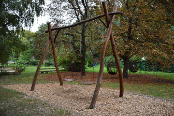 Decorative wooden swing for two seats on the background of a summer park