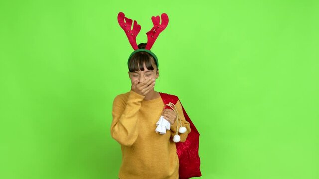 Young woman with christmas hat smiling a lot while covering mouth over isolated background. Green screen chroma key