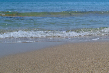 Fototapeta na wymiar Sea wave with foam on the sandy shore.