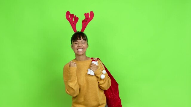Young woman with christmas hat celebrating a victory and surprised to be successful over isolated background. Green screen chroma key