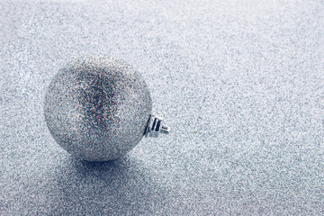 Christmas ball with sparkles on silver glitter background