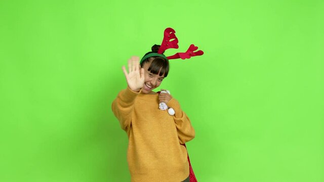 Young woman with christmas hat saluting with hand with happy expression over isolated background. Green screen chroma key